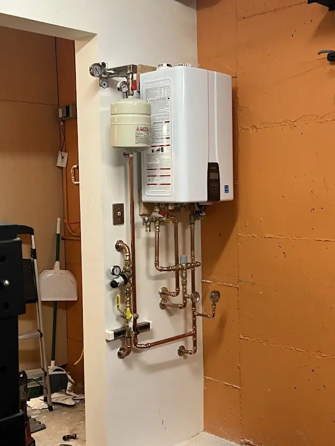 Plumbing technician inspecting water heater connections in Perinton